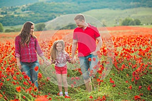 Pregnant woman her husband and their daughter in poppy field