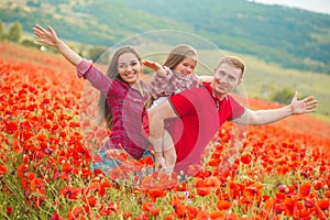 Pregnant woman her husband and their daughter in poppy field