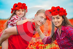 Pregnant woman her husband and their daughter in poppy field