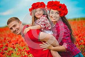 Pregnant woman her husband and their daughter in poppy field