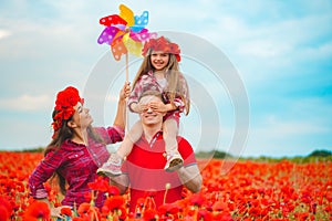 Pregnant woman her husband and their daughter in poppy field