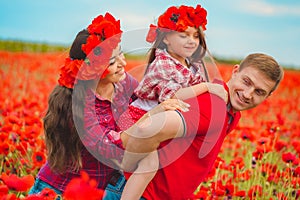 Pregnant woman her husband and their daughter in poppy field