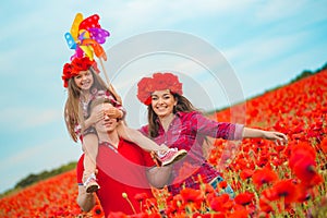 Pregnant woman her husband and their daughter in poppy field