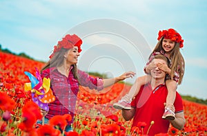 Pregnant woman her husband and their daughter in poppy field