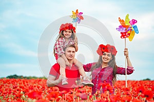 Pregnant woman her husband and their daughter in poppy field