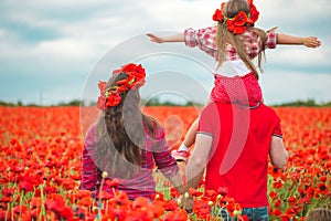 Pregnant woman her husband and their daughter in poppy field