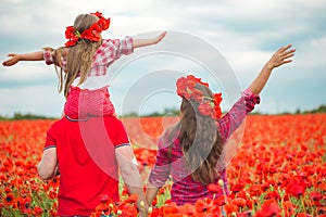 Pregnant woman her husband and their daughter in poppy field