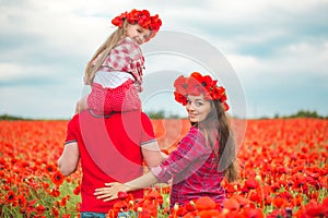 Pregnant woman her husband and their daughter in poppy field