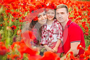 Pregnant woman her husband and their daughter in poppy field