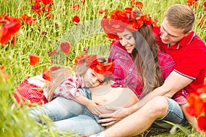 Pregnant woman her husband and their daughter in poppy field