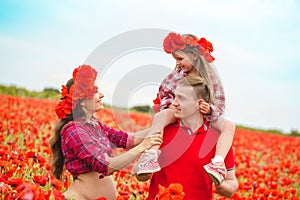 Pregnant woman her husband and their daughter in poppy field