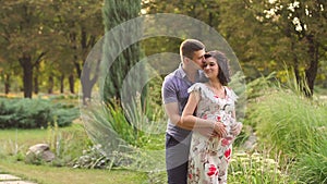 Pregnant woman with her husband walking in Park.