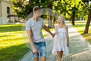 Pregnant woman with her husband walking in a park