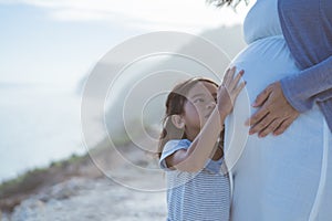 Pregnant woman with her little cute daughter in the beach