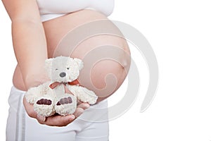 Pregnant woman hold in hand white toy bear