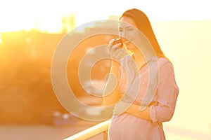 Pregnant woman holding an apple and looking at you