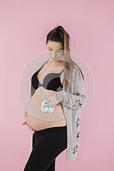 Pregnant woman holding baby booties against her belly