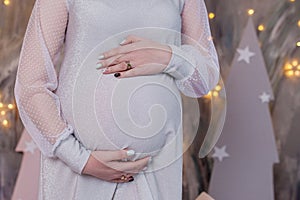 Pregnant woman holding baby booties. Belly with booties close up