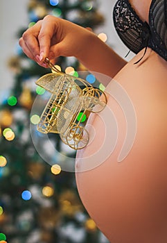 Pregnant woman holding baby buggy near her belly