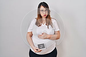 Pregnant woman holding baby ecography puffing cheeks with funny face