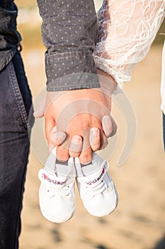 Pregnant woman holding baby shoes