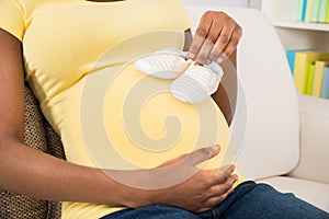 Pregnant Woman Holding Baby Shoes