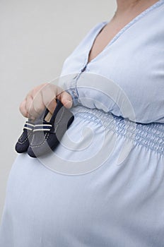 Pregnant woman holding baby shoes