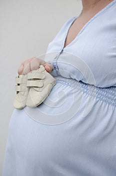 Pregnant woman holding baby shoes