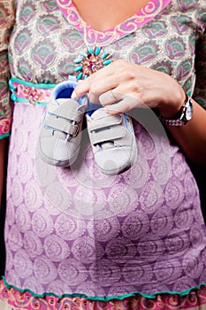 Pregnant woman holding baby shoes