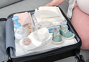 Pregnant woman holding baby shoes and packing maternity hospital bag. Mother during pregnancy waiting for baby preparing