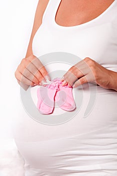 Pregnant woman holding baby socks on her pregnant belly