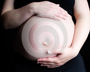 Pregnant woman holding belly on black