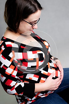 Pregnant woman holding belly and smiling