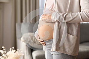 Pregnant woman holding big bare baby bump close up