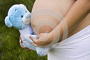 Pregnant woman holding a blue bear