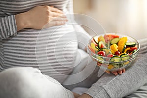 Pregnant Woman Holding Bowl With Fresh Vegetable Salat While Sitting On Bed