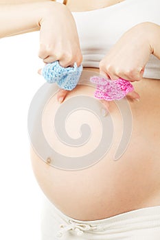 Pregnant woman holding boy and girl clothes