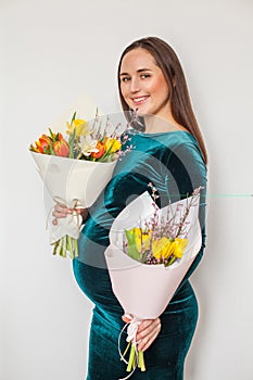 Pregnant woman holding bright flowers on white background