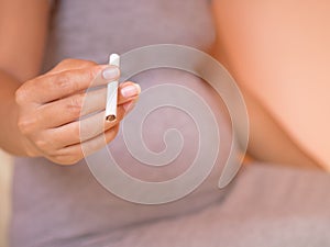 Pregnant woman holding cigarette. What harm baby.