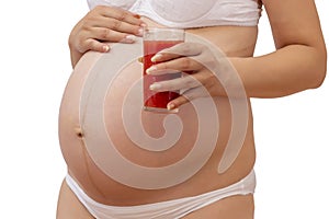 Pregnant woman holding cold glass of tomato juice at her tummy