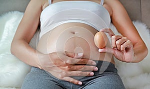 Pregnant woman holding an egg at her belly