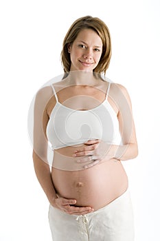 Pregnant woman holding exposed belly smiling