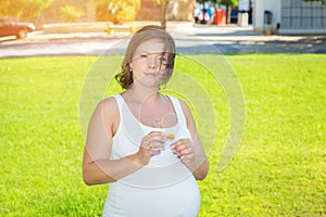 Pregnant Woman holding flower guessing the gender of her baby