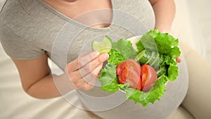 Pregnant woman is holding fresh vegetables in her hand. Concept of healthy eating during pregnancy.