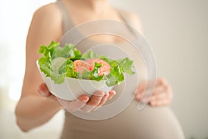 Pregnant woman is holding fresh vegetables in her hand. Concept of healthy eating during pregnancy.