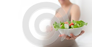 Pregnant woman is holding fresh vegetables in her hand. Concept of healthy eating during pregnancy.