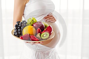 Pregnant woman holding fruit plate