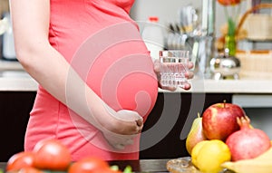 Pregnant woman holding a glass of clean water whil