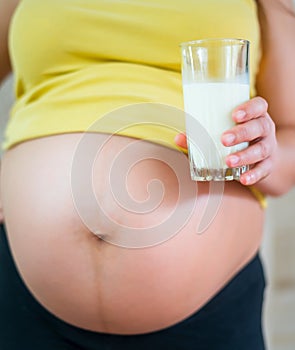 Pregnant woman holding a glass of fresh milk