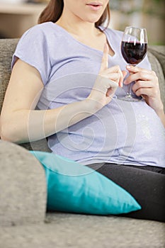 pregnant woman holding glass and saying no to alcohol